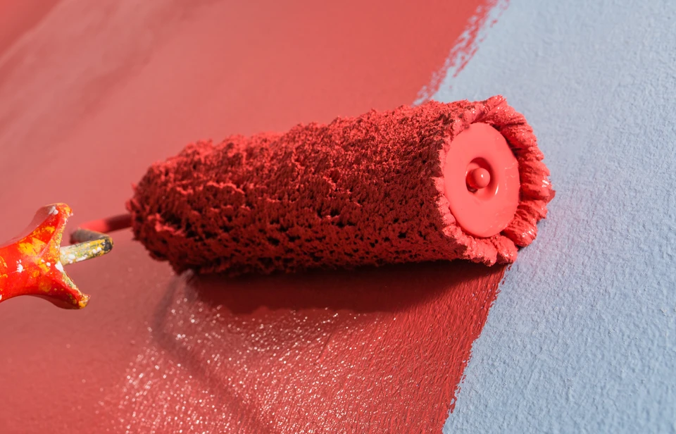 Peinture murale en cours avec rouleau à peinture rouge appliquant une couche sur surface blanche