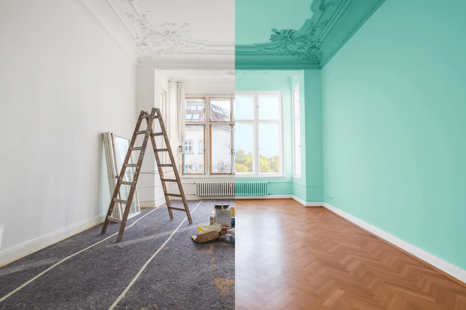 Rénovation d'appartement en cours avec peinture murale turquoise appliquée sur la moitié droite d'une pièce aux moulures décoratives