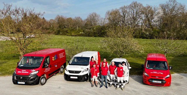 Ouvrier en équipement de sécurité applique une peinture de façade extérieure à l'aide d'un rouleau sur mur blanc d'habitation résidentielle